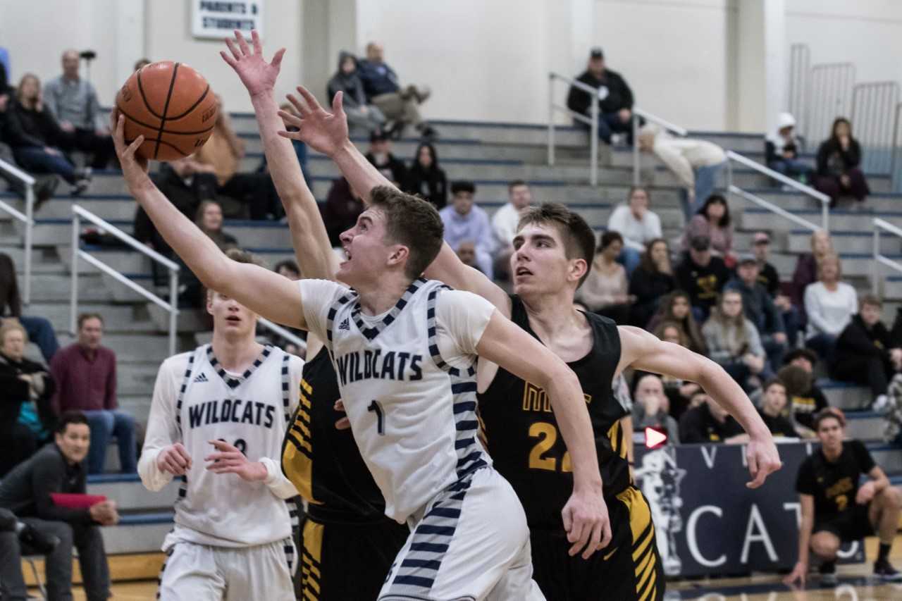 Wilsonville's Gabe Reichle (1) drives past Milwaukie's Mason Plumb (22) on Tuesday night. (Photo by Greg Artman)