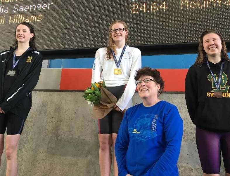 Aloha's Kaitlyn Dobler (center), with coach Lisa Leslie (foreground), reset two of her OSAA meet records Saturday.