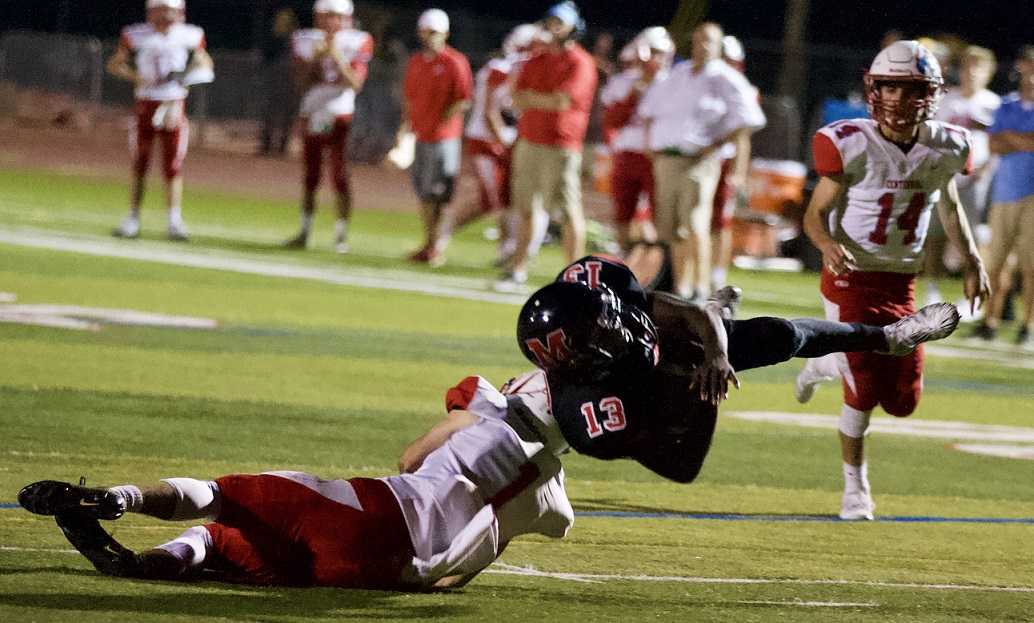 McMinnville’s Kerby Hartzell (13) goes airborne after a tackle by Centennal’s Dillon Hart on Friday. (Photo by Norm Maves Jr.)