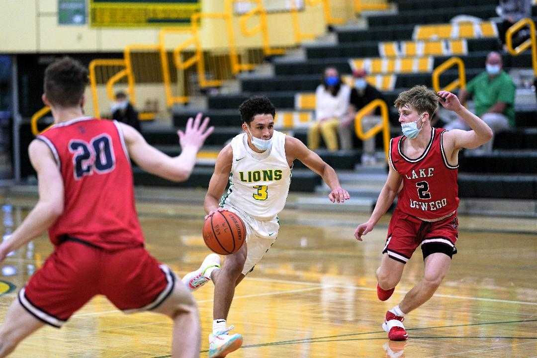 West Linn's Jackson Shelstad drives between Lake Oswego's Carson Reno (2) and Christian Rowell (20). (Photo by Jon Olson)