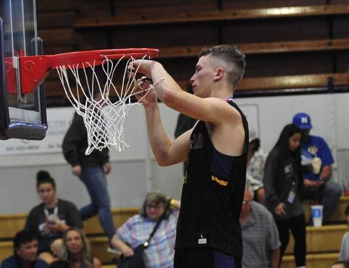 Marshfield's Noah Niblett cuts down the net after his team's win over Cascade on Friday. (Photo courtesy The World)