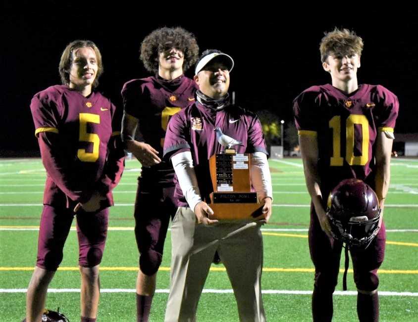 Coach Dominic Ferraro holds the Pigeon Bowl trophy after Forest Grove defeated McMinnville 24-21 last season.