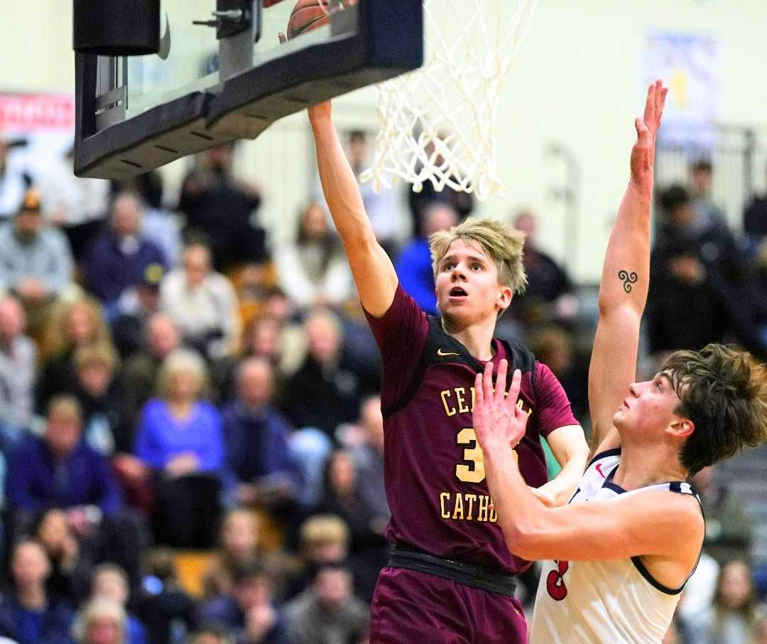 Central Catholic's Isaac Carr goes over Lake Oswego's Max Archambo for two of his 19 points Monday. (Photo by Jon Olson)