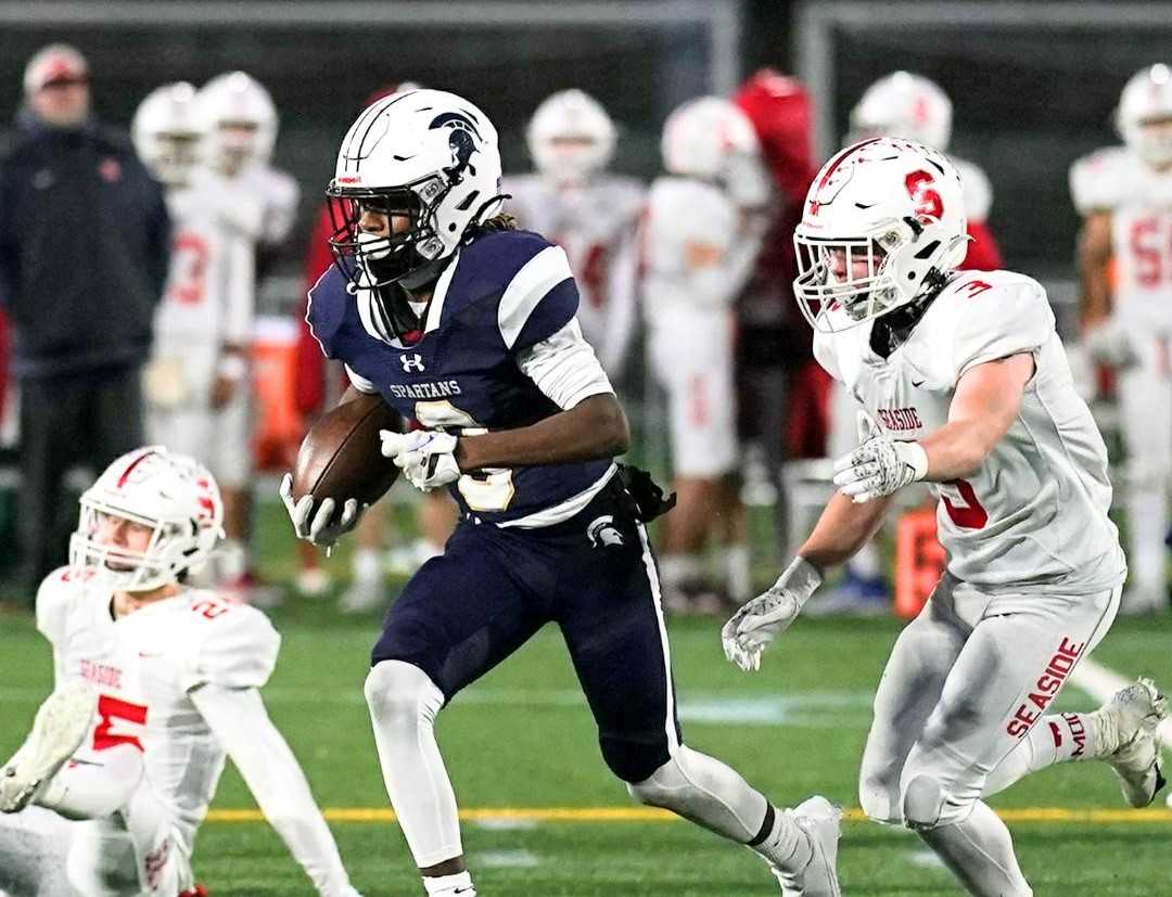 Marist Catholic's Dennis Jackson Jr. evades Seaside's Tallen Kraushaar in Saturday's 4A football semifinal. (Photo by Jon Olson)