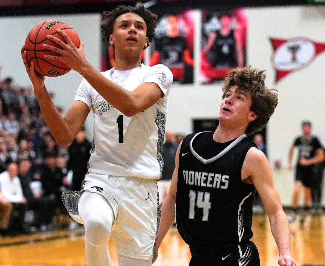 Tualatin sophomore guard Jemai Lake drives to the basket against Oregon City's Alex Hoff on Friday night. (Photo by Jon Olson)