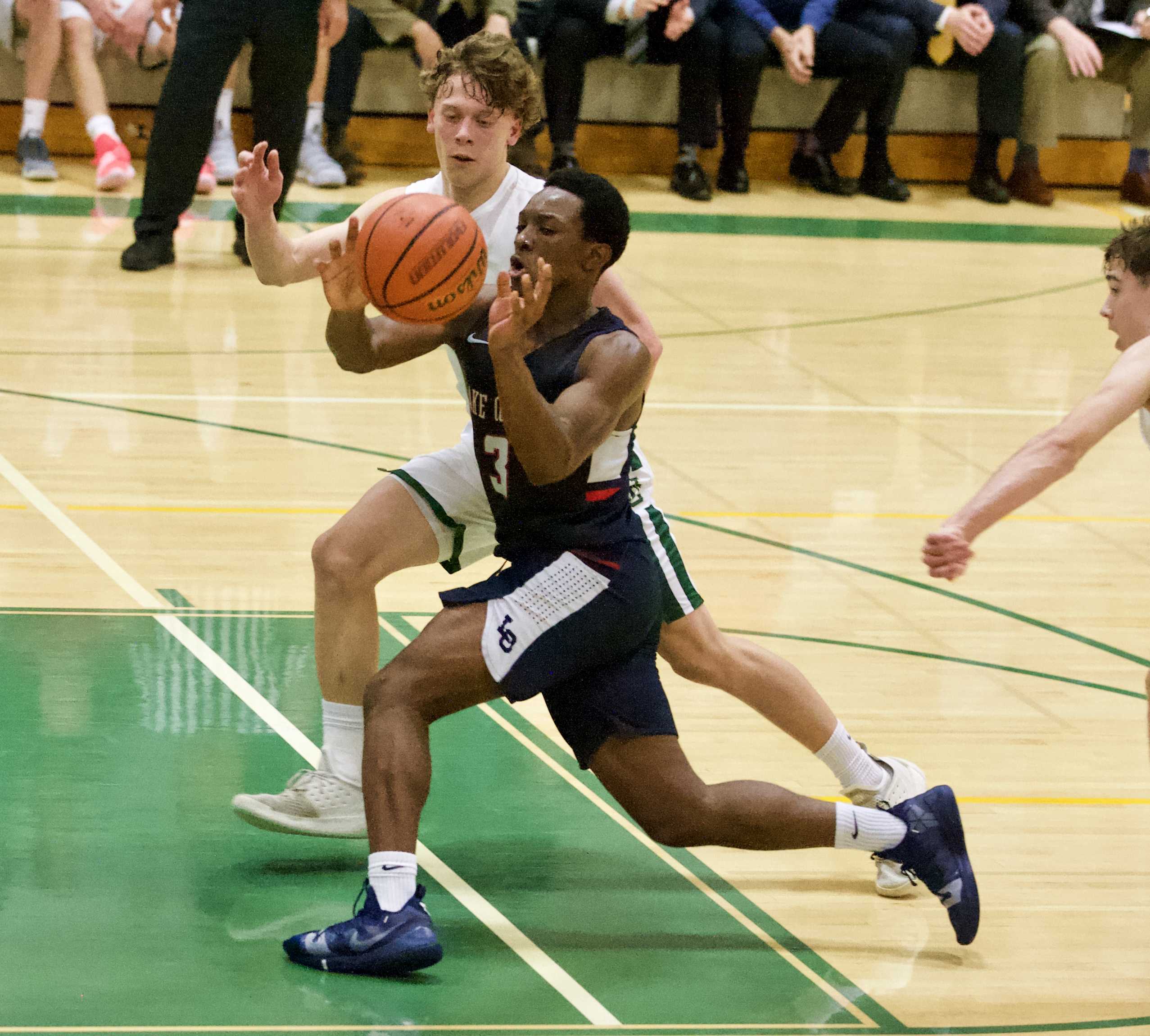 Lake Oswego's Wayne McKinney drives past Jesuit's Matthew Levis. (Photo by Norm Maves Jr.)