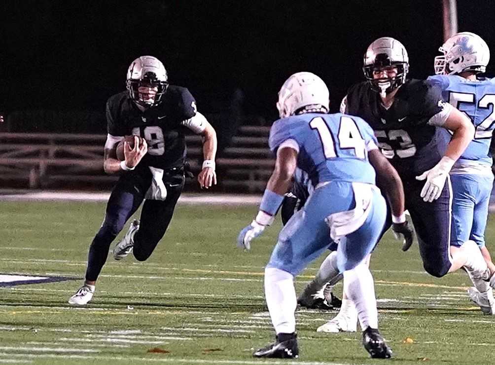 Lake Oswego quarterback Hudson Kurland looks to evade Lakeridge's Yahkyll Noil (14) on Friday night. (Photo by J.R. Olson)