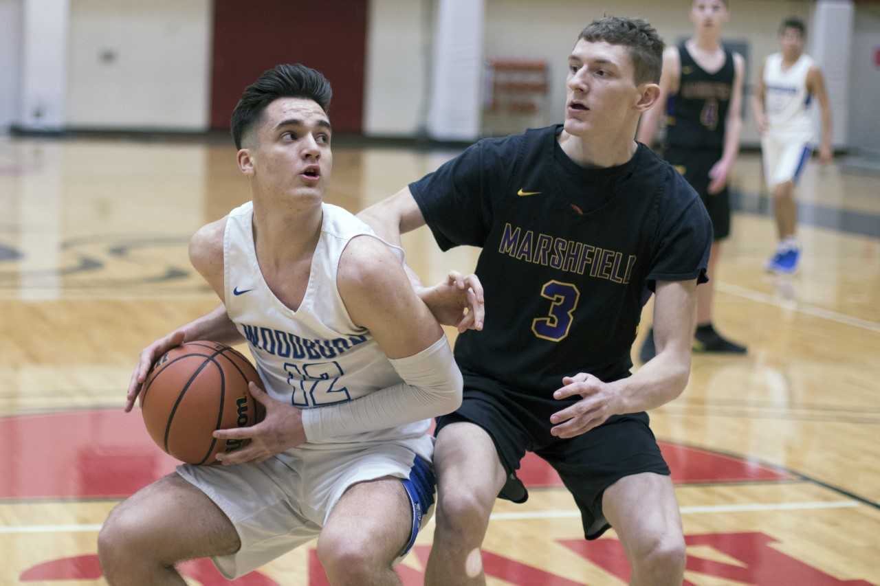 Woodburn senior point guard RJ Veliz (12) goes up for a layup against Marshfield senior guard Jacob Carpenter (3).