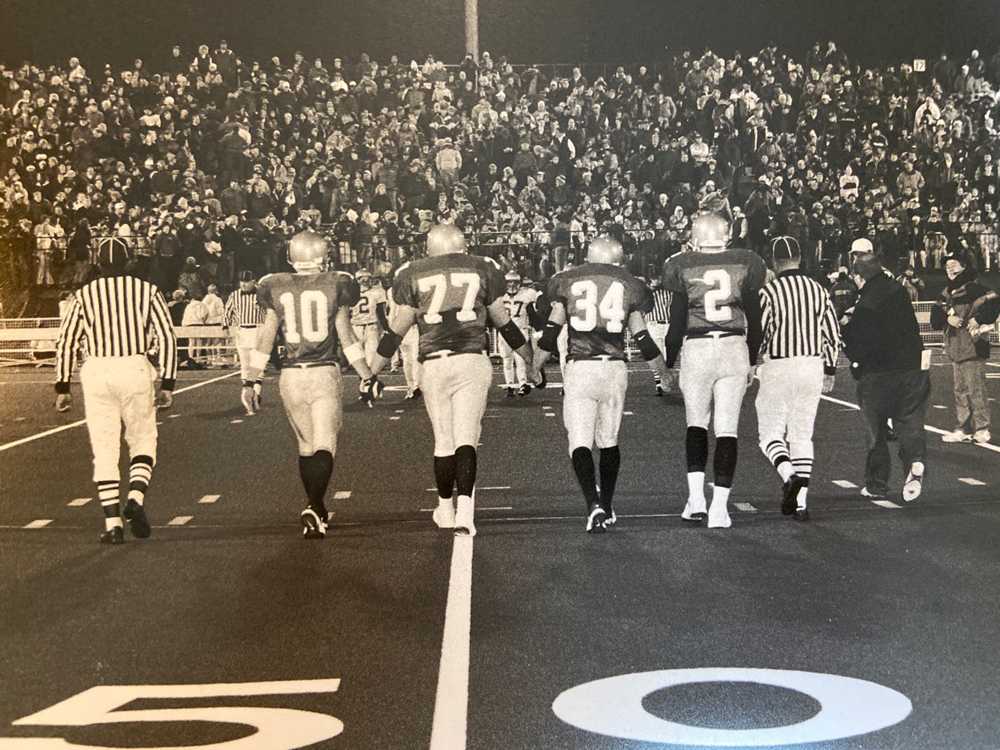 Mike Hass (10) and his fellow Jesuit captains walk to midfield for the coin toss before a packed house