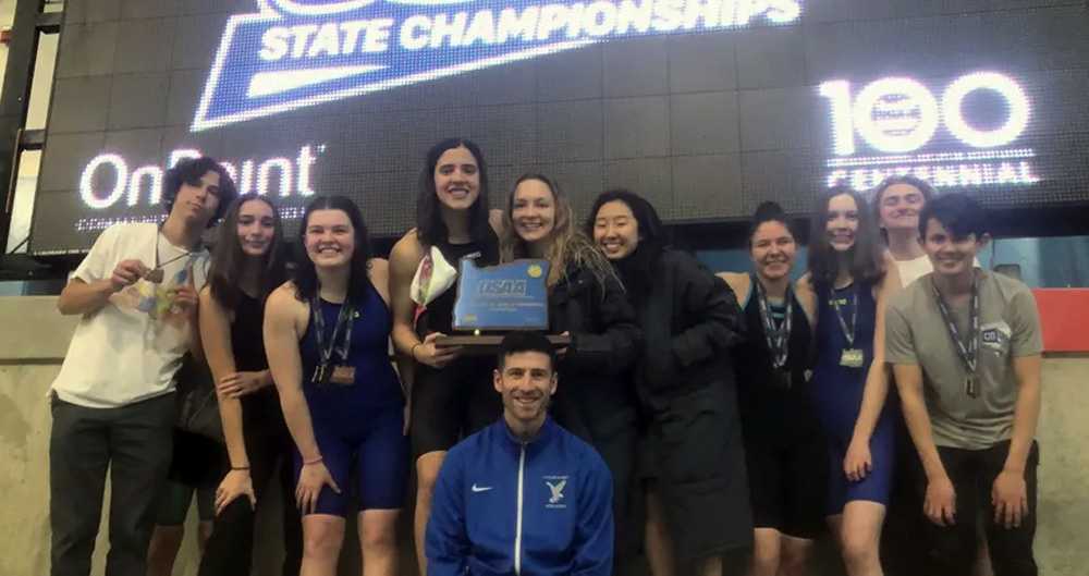 Swim team members from Catlin Gabel's most recent state championship pose with the coach and the blue trophy