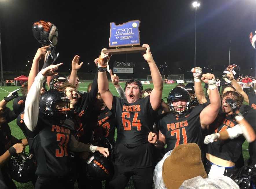 Silverton's Samuel Willis (64) hoists the 5A trophy after the Foxes beat Thurston 26-20 on Saturday at Hillsboro Stadium.