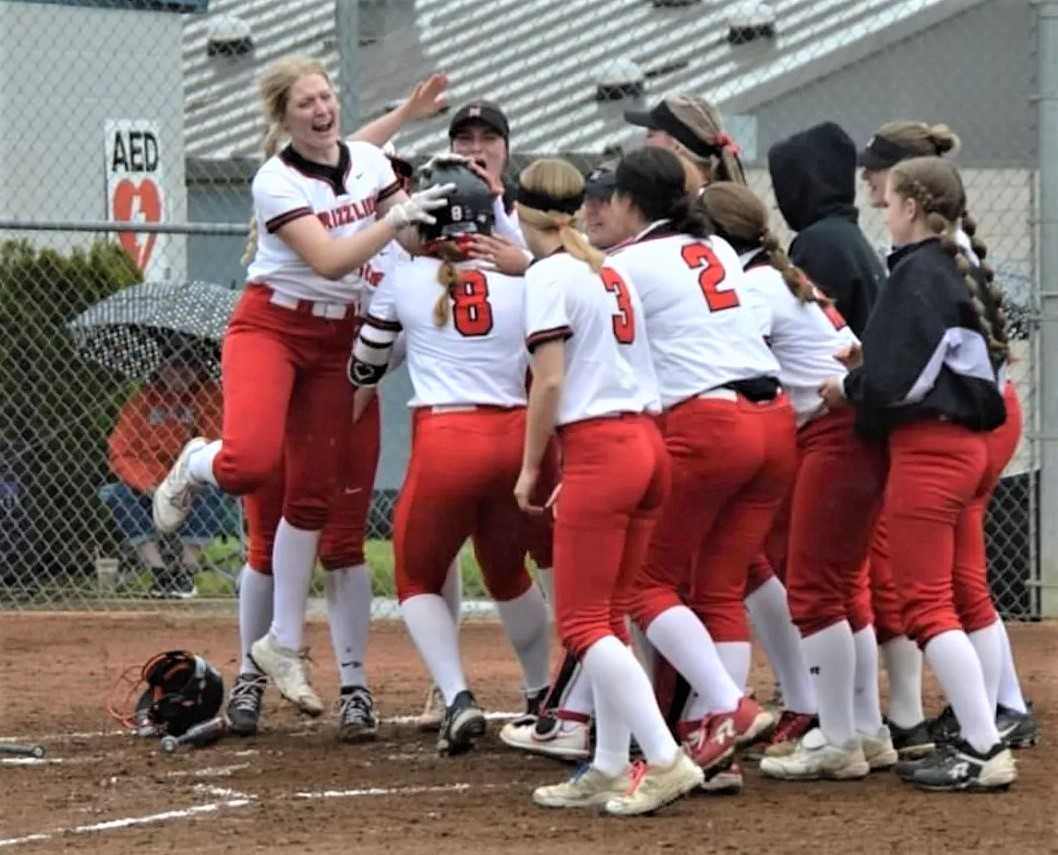 McMinnville players celebrate with Brynn McManus (8) after her first home run against Newberg. (Photo by Kara Stigall)