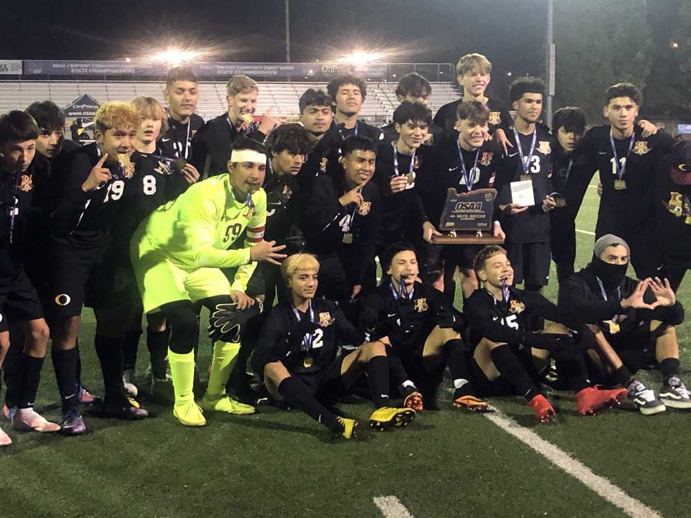 Ontario goalie Martin Benites (in yellow) and his Tiger teammates celebrate the first state title for the Eastern Oregon school