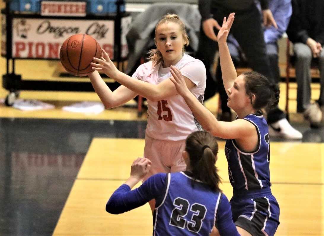 Oregon City's Mollie Miller works around the defense of McNary's Avery Buss (23) and Bella Rodriguez. (Photo by Norm Maves Jr.)