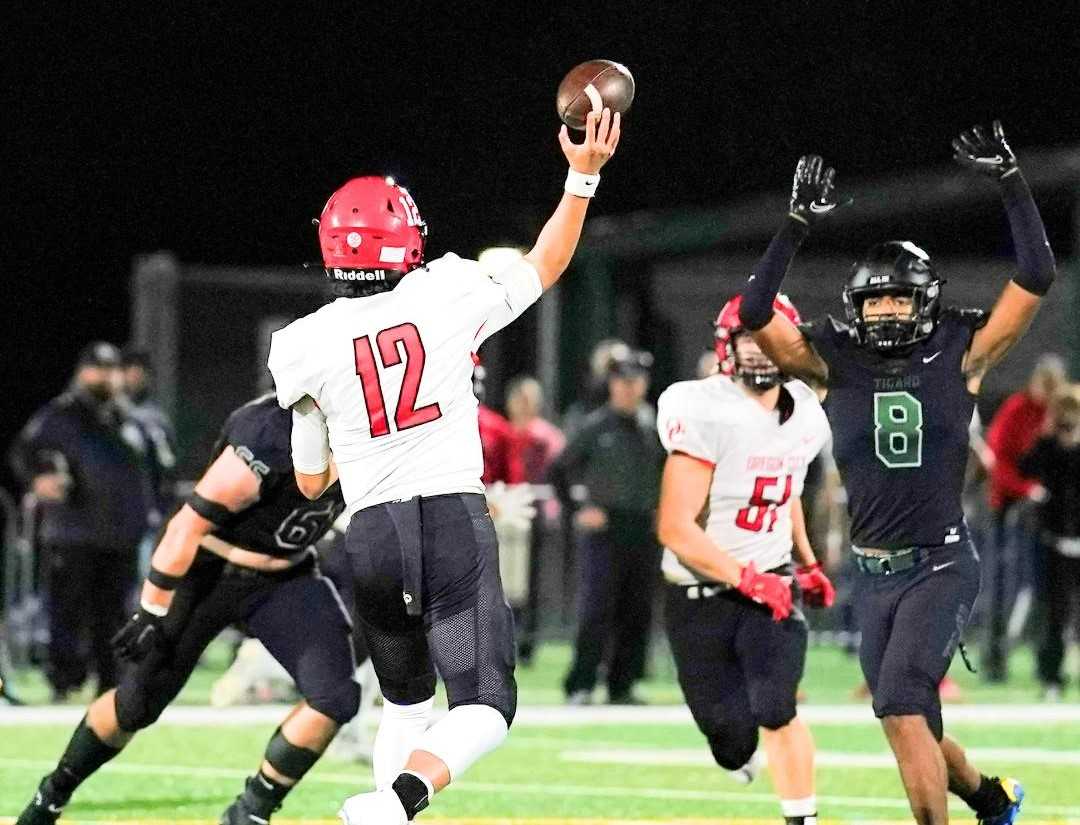 Oregon City's Ben Schneider (12) throws over the outstretched arms of Tigard's Brian Smith on Friday night. (Photo by JonOlson)