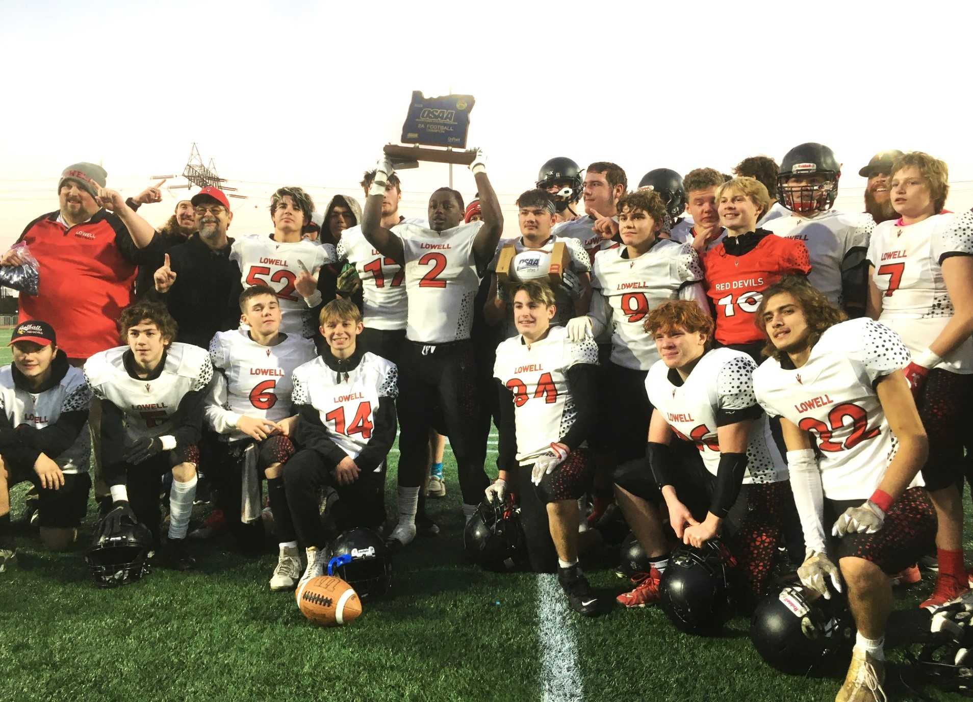 JaMar Thurman (2) hoists the state championship trophy after Lowell's win in the 2A football final Saturday afternoon.