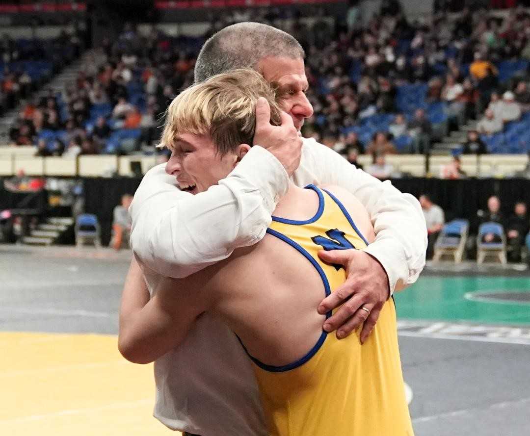 Newberg's Isaac Hampton embraces coach Neil Russo after winning his third 6A title Saturday night. (Photo by Jon Olson)