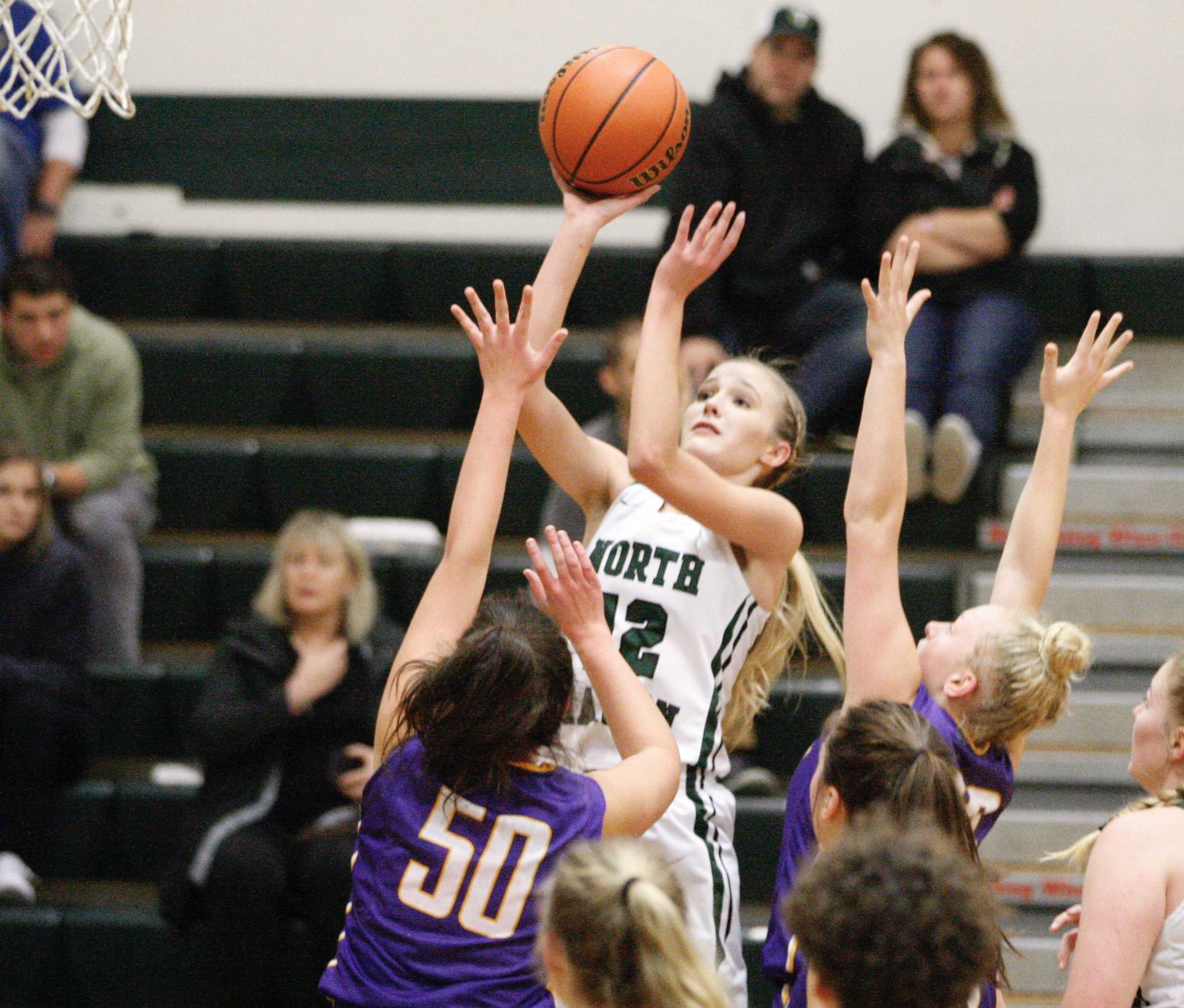 North Marion junior Katie Ensign goes over Gracie Brugnoli (50) and McKayla Myrand of Marshfield for two of her 18 points.