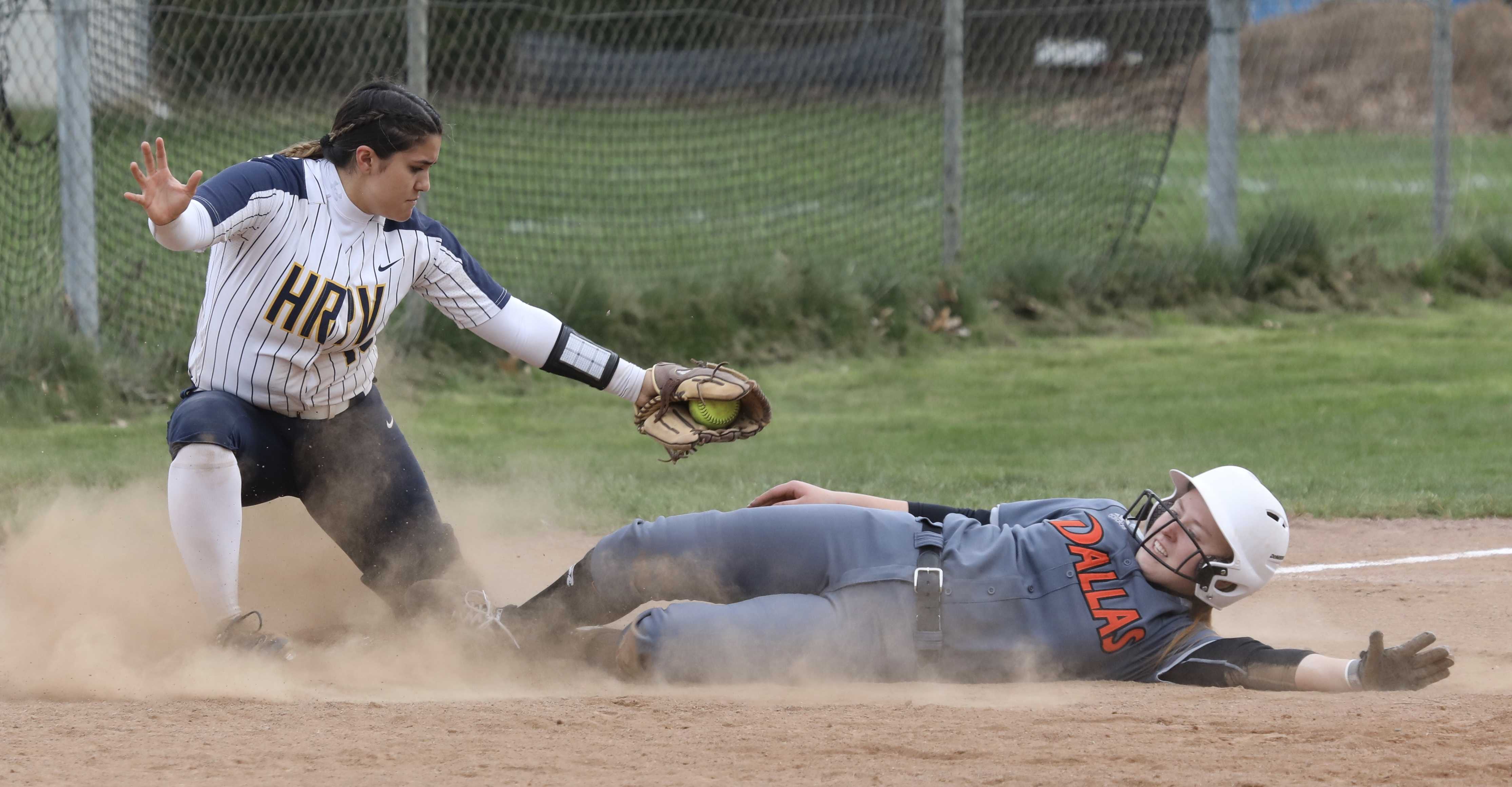 Dallas sophomore Morgan Dippel slides safely under the tag of Hood River Valley third baseman Aunika Yasui during Dragon rally.